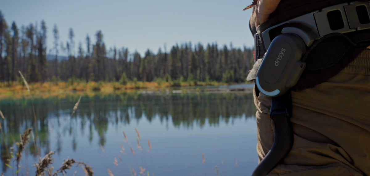 Gros plan sur un exosquelette DNSYS X1 porté au bord d’un lac
